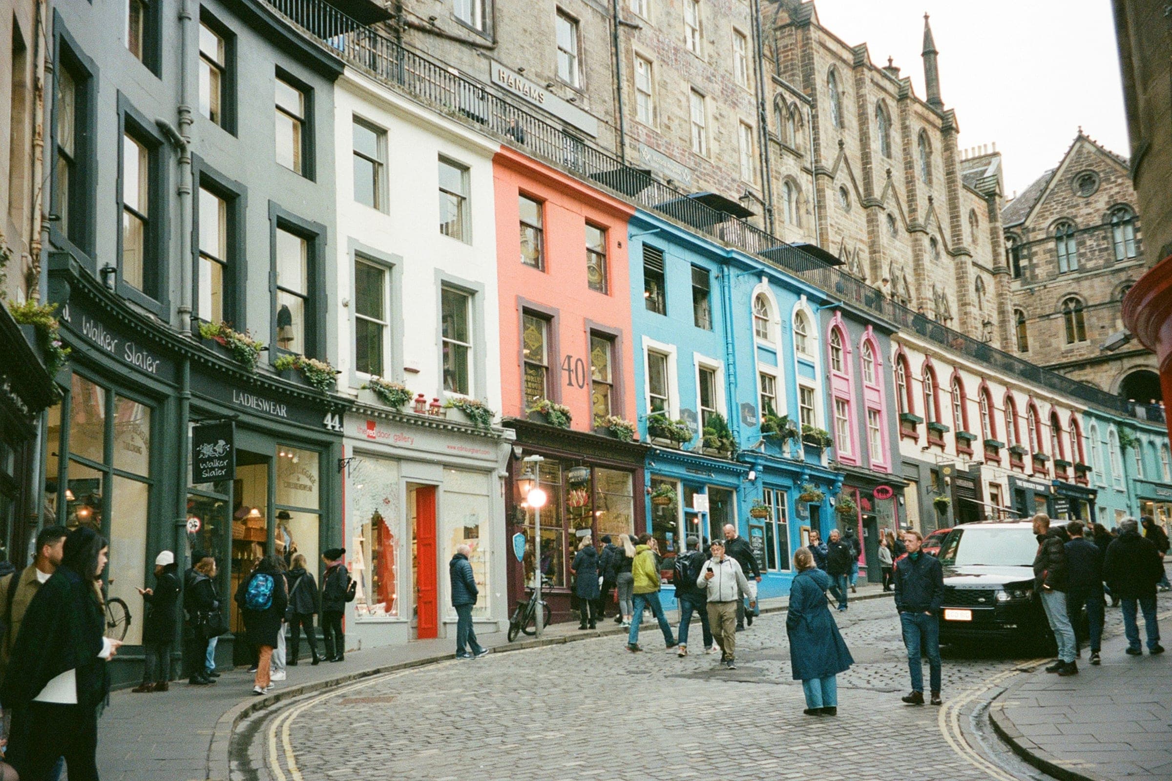 People walking down colourful Victoria Street in Edinburgh’s Old Town on a bright day