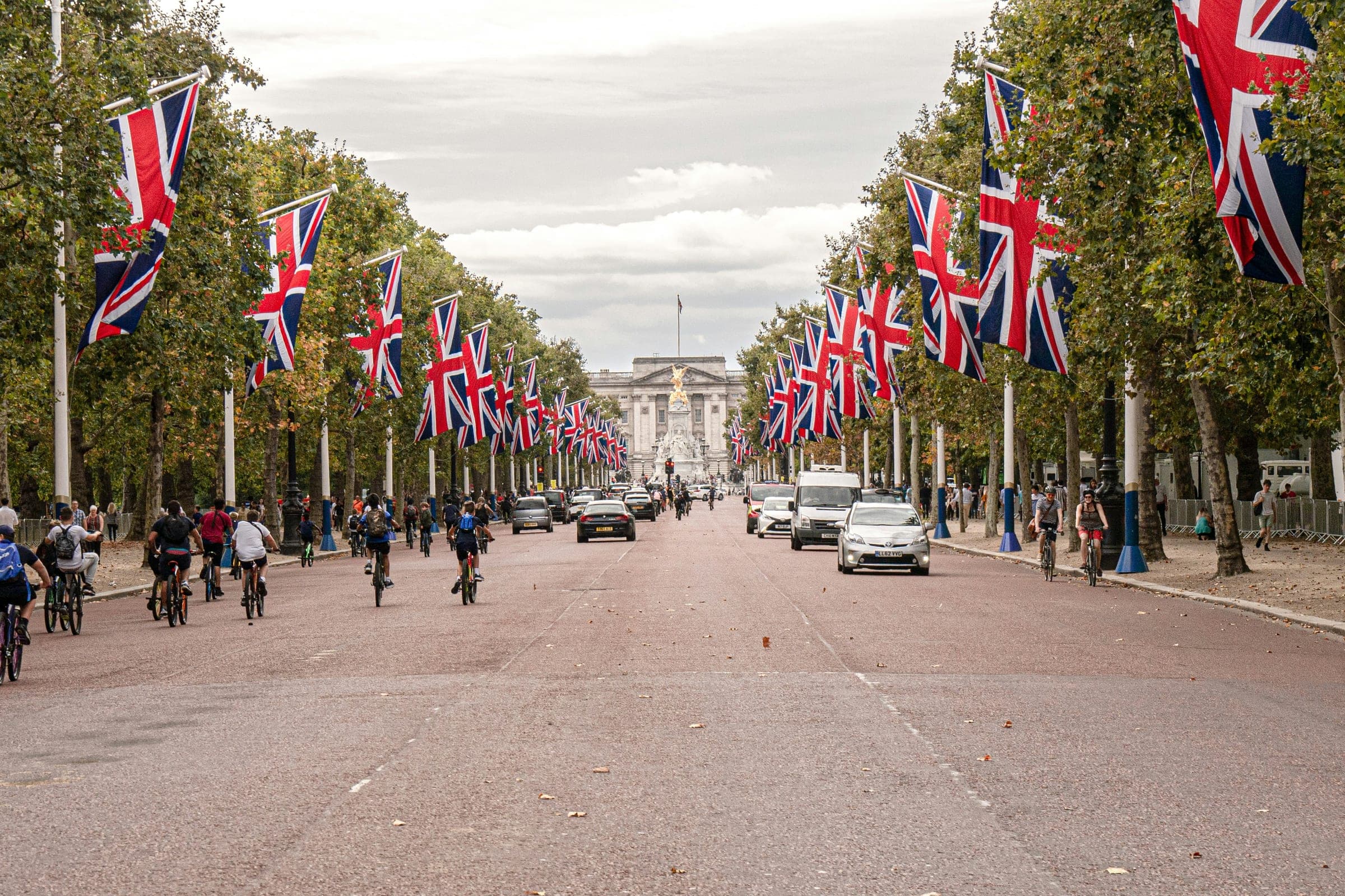 Cyclists riding up The Mall towards Buckingham Palace, lined with Union flags